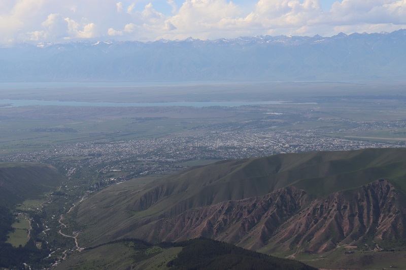 Pohľad dole na mesto Karakol a veľké jazero Issyk-Kul za ním.